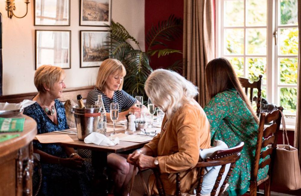 a group of ladies sat around a table with glasses of prosecco